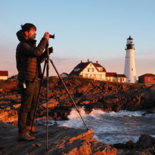 Photographer capturing a sunrise at Portland Head Lighthouse in Maine