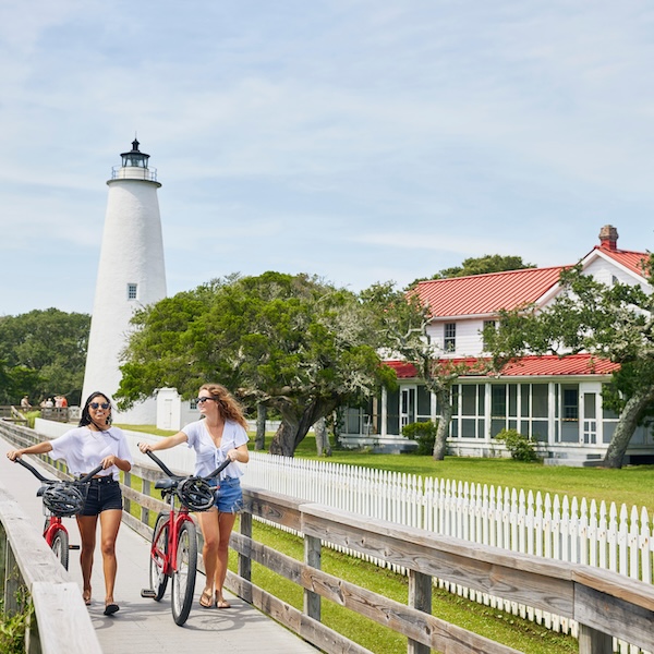 Two girls with bikes in front of the lighthouse on Ocracoke Island on the Outer Banks of North Carolina