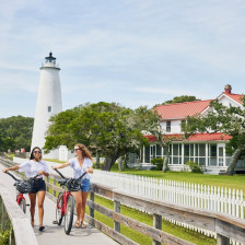 Two girls with bikes in front of the lighthouse on Ocracoke Island on the Outer Banks of North Carolina