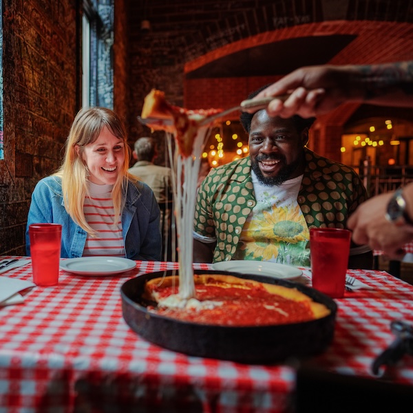 Visitors trying deep dish pizza at Gino's East in Chicago, Illinois