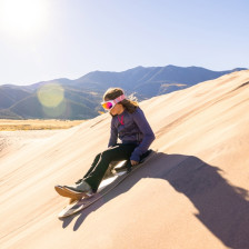 Visitor sandboarding down a dune at Great Sand Dunes National Park in Colorado