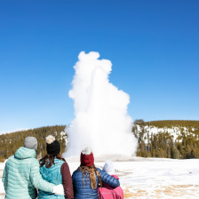 Family watching Old Faithful in Yellowstone National Park in winter