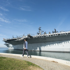 Man walking past the USS Midway Museum in San Diego, California