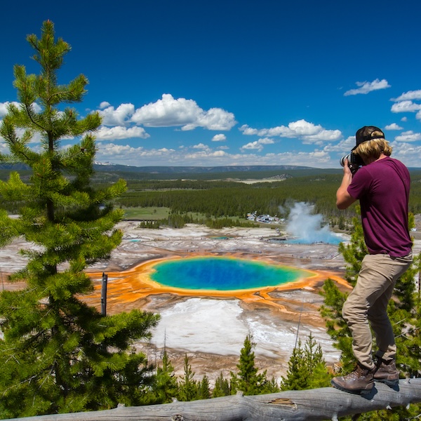 Man taking a picture of the Grand Prismatic Spring in Yellowstone National Park